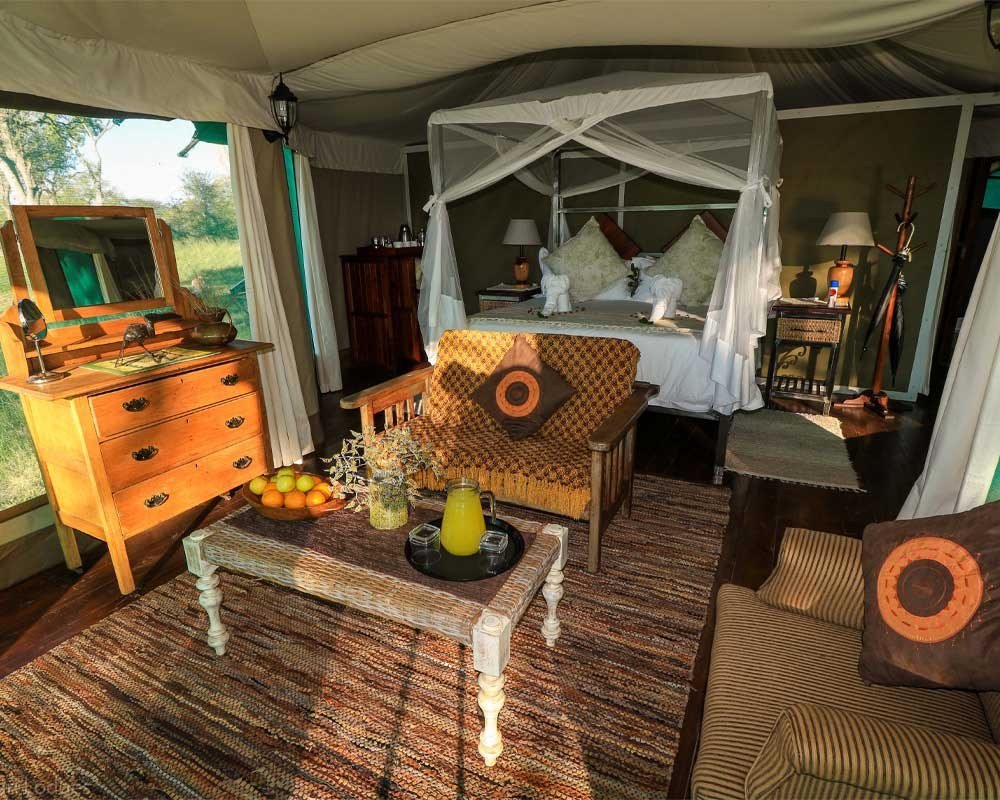 A tent interior at Bomani Tented Lodge has a canopy bed, rug and wooden dresser