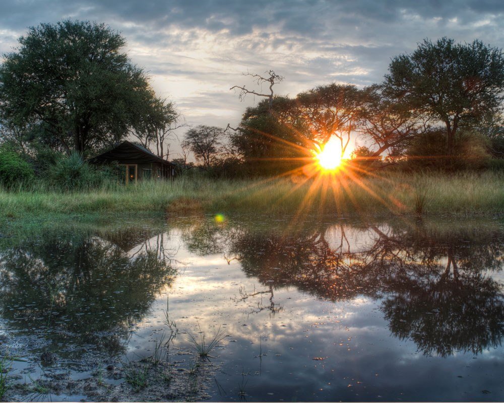 At Bomani Tented Lodge, the sun sets over a pan, reflected in the still water