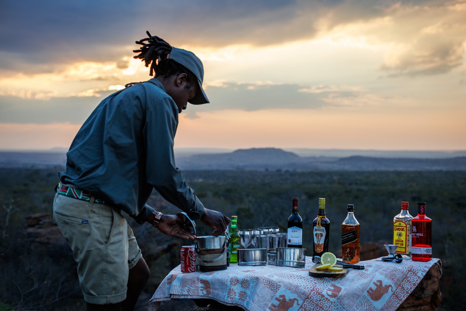 A guide setting up sundowners on a ridge at dusk