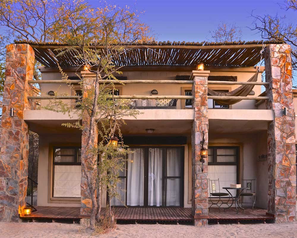 Camelthorn Lodge's two-storey stone villa has a shaded balcony, pictured at dusk in Hwange