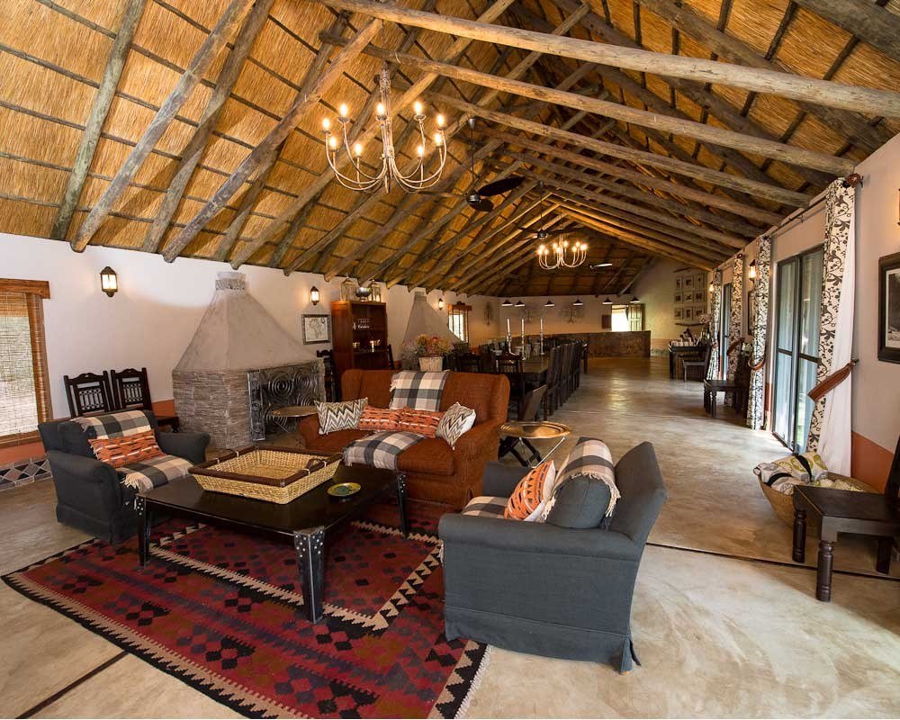 Camelthorn Lodge's main lounge sits under a high thatched roof with a fireplace