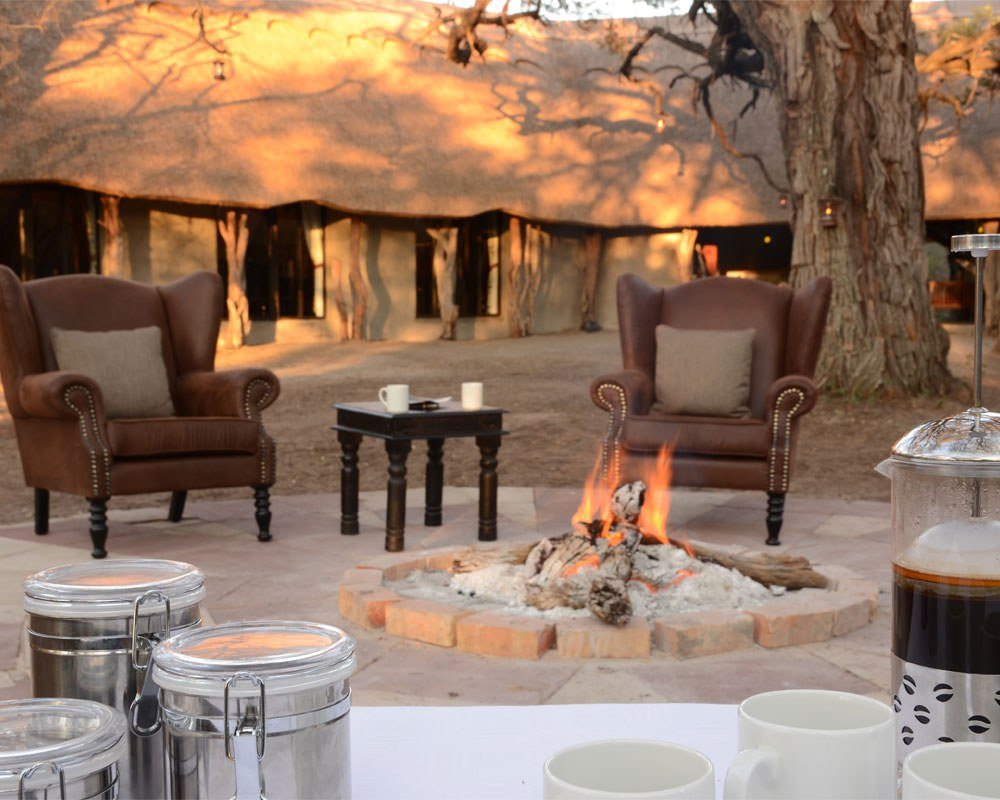 Armchairs are set around the fire pit in front of Camelthorn Lodge