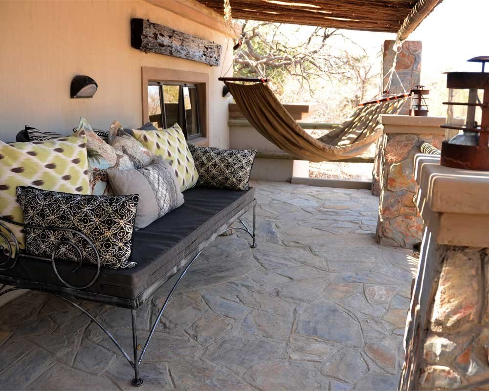 A villa veranda at Camelthorn Lodge has a cushioned daybed and a hammock