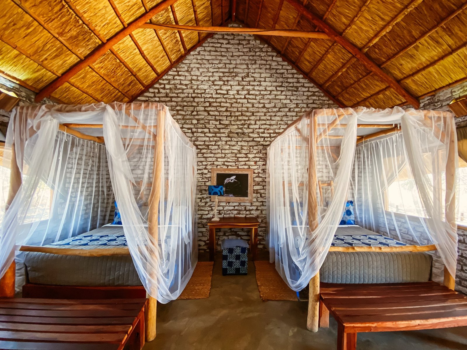 A deluxe chalet at Gwango Heritage Resort has two canopy beds under a thatched roof