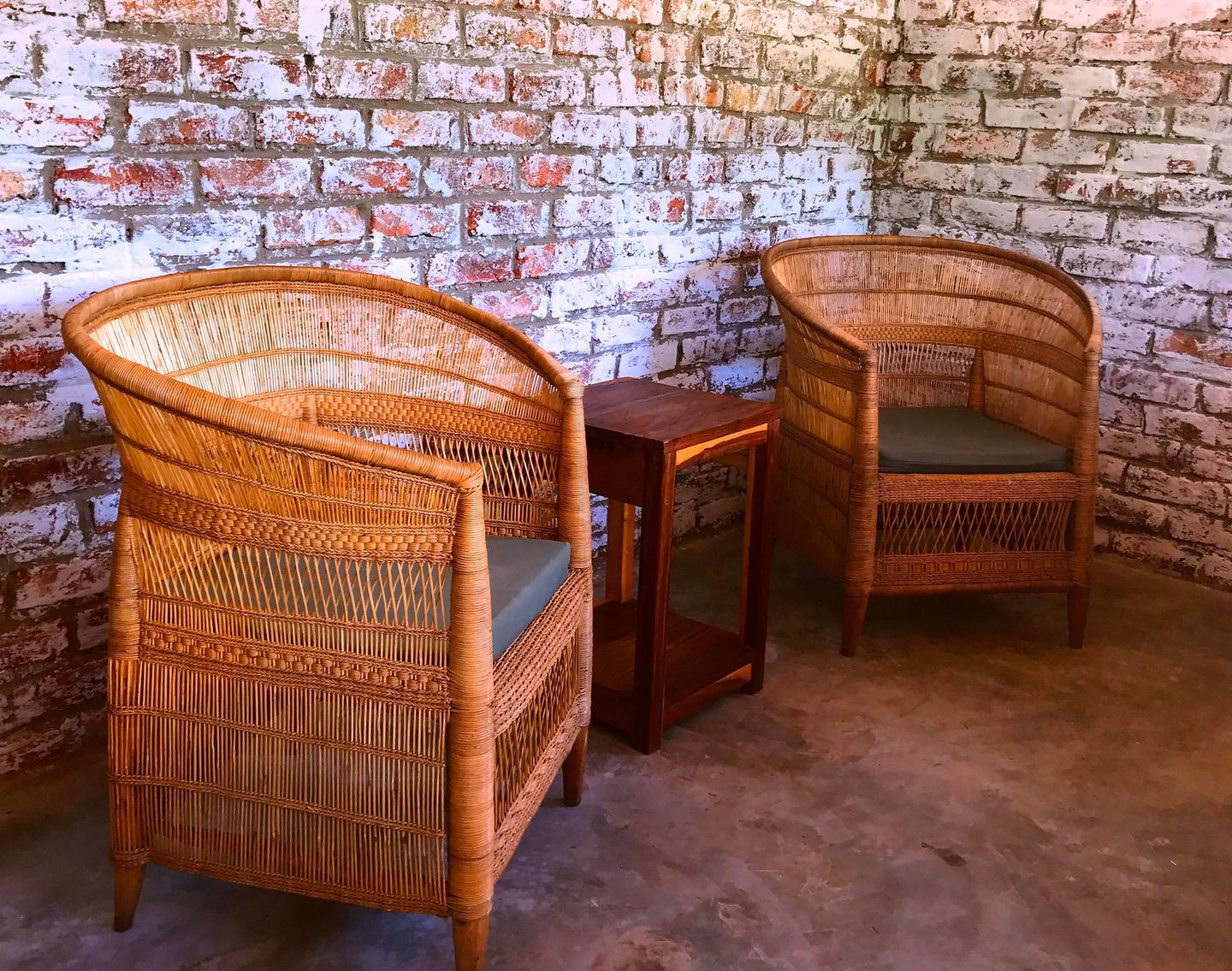 Wicker chairs sit on a chalet veranda at Gwango Heritage Resort against a whitewashed wall
