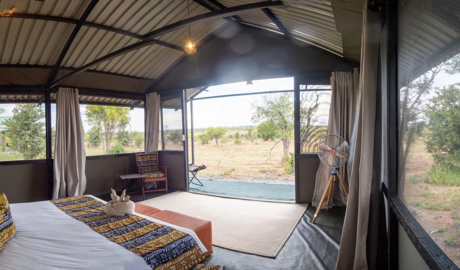 A bedroom at Hwange Bush Camp opens wide onto the bush through a full-length doorway