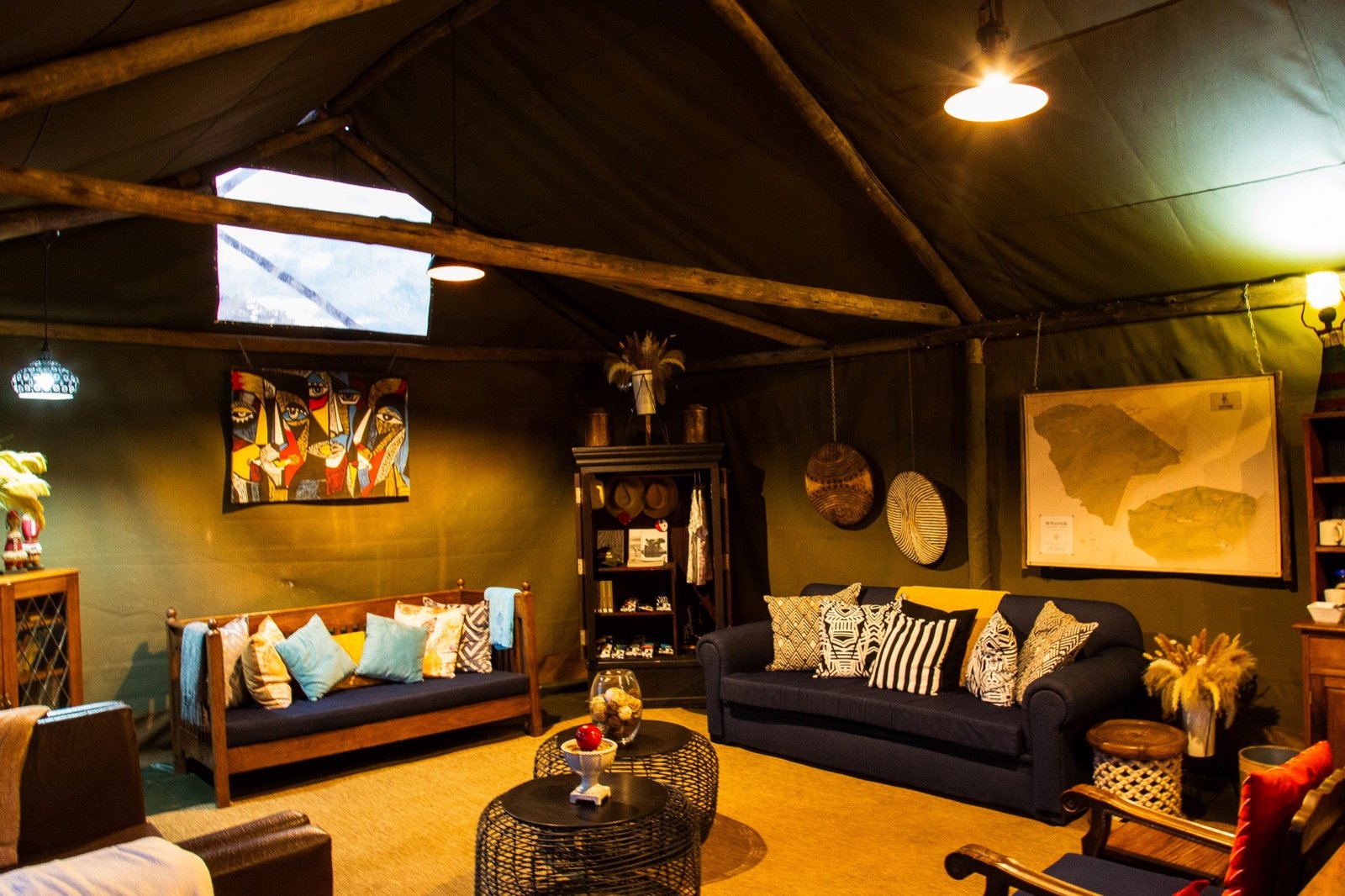 Hwange Bush Camp's lounge has sofas, patterned cushions and a large wall map