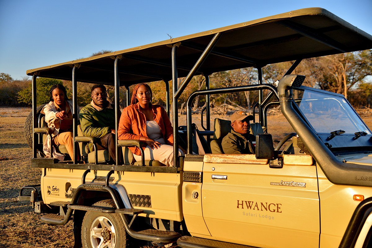 Guests sit in Hwange Safari Lodge's open game vehicle, ready for a drive