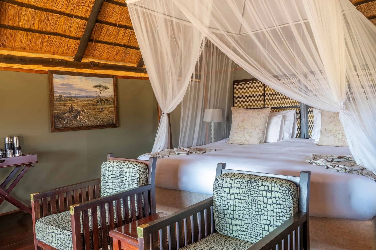A bedroom at Ivory Lodge has a canopy bed and mosquito net under thatch
