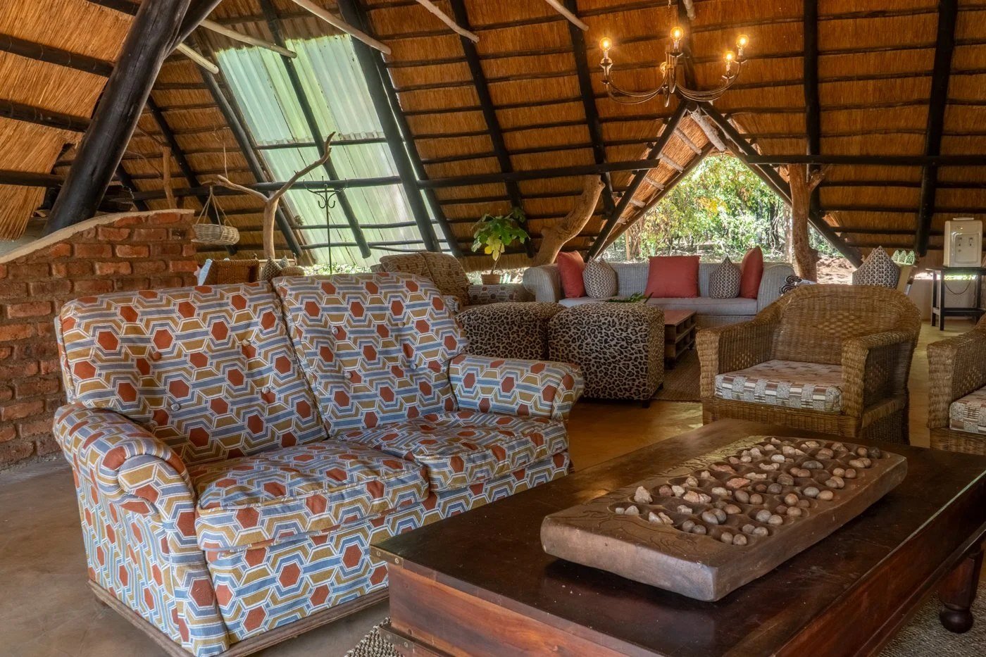 Ivory Lodge's main lounge sits under a high thatched roof with patterned sofas