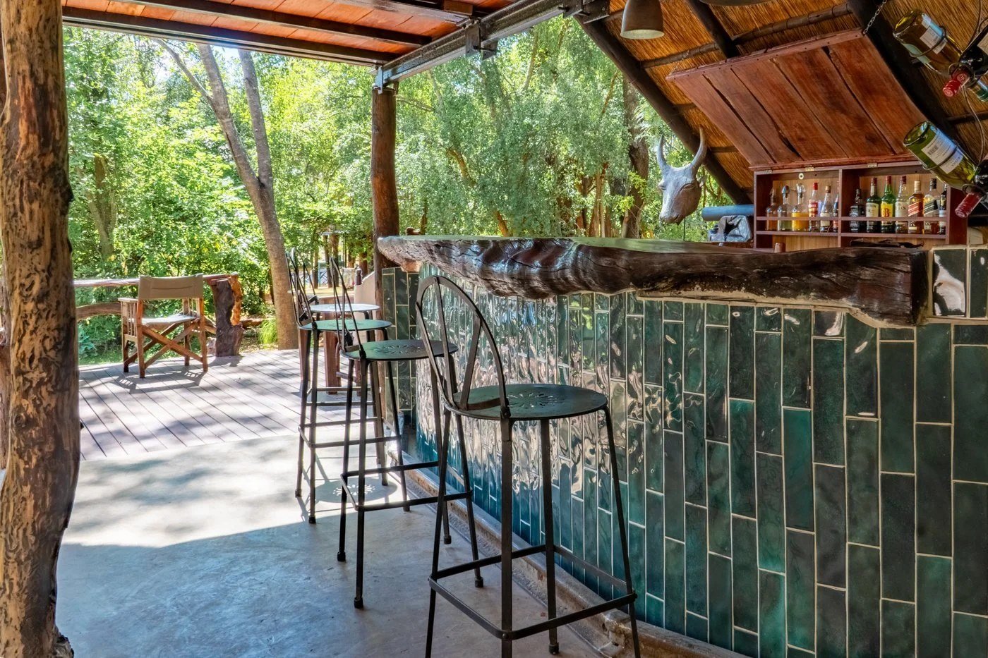 Ivory Lodge's bar counter has green tiles and stands open to the trees