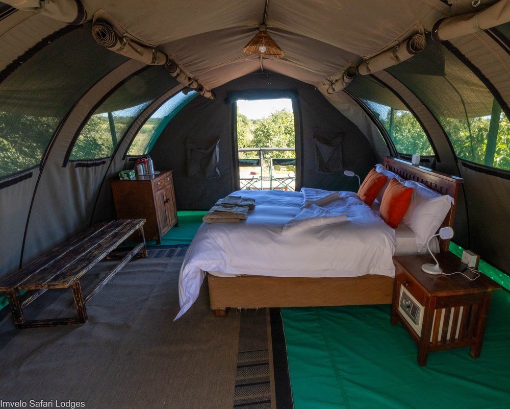 Inside a dome tent at Jozibanini Camp, a double bed faces the open door