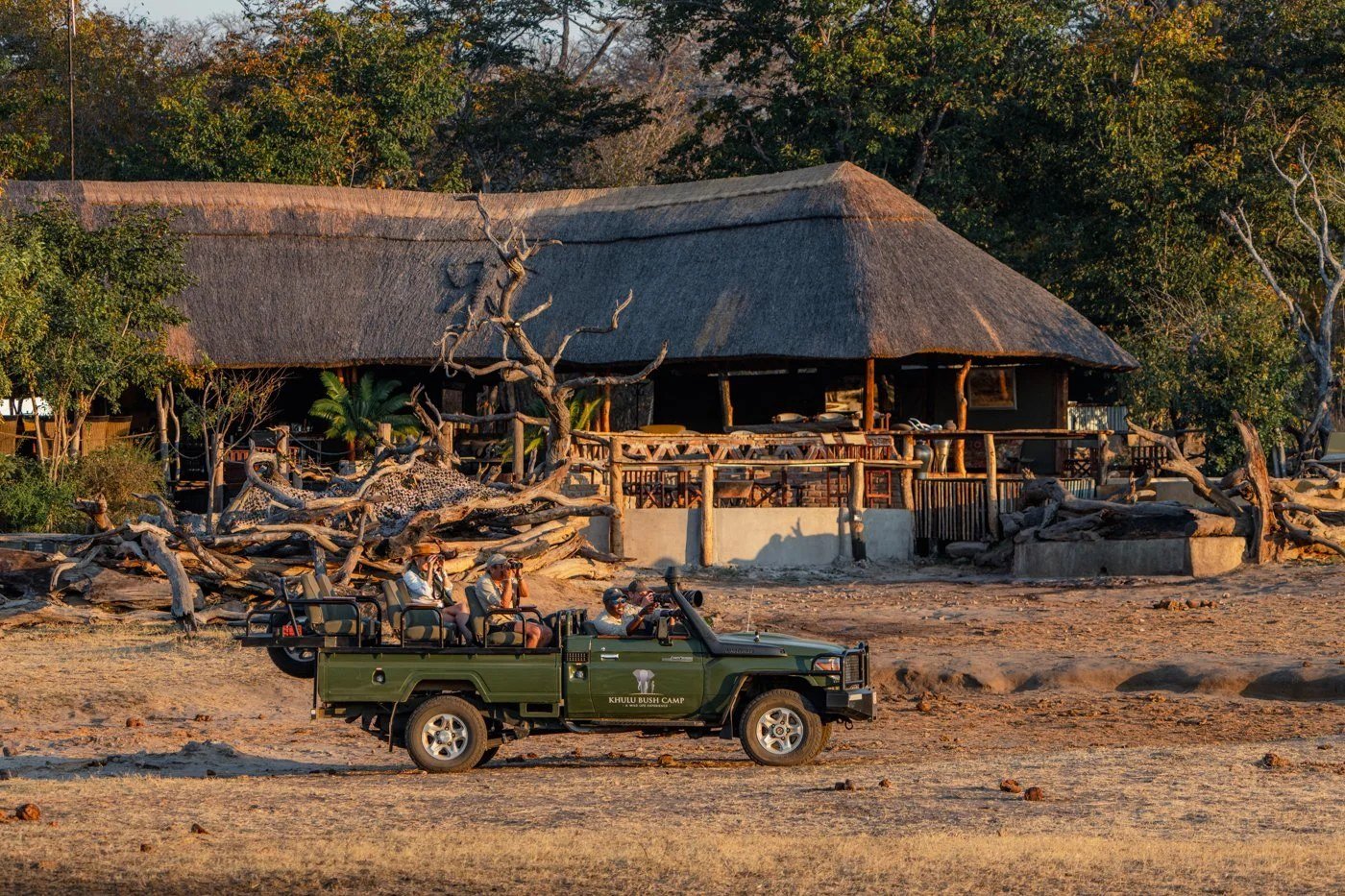 A game vehicle parks in front of Khulu Bush Camp's main area, behind deadwood, in Hwange