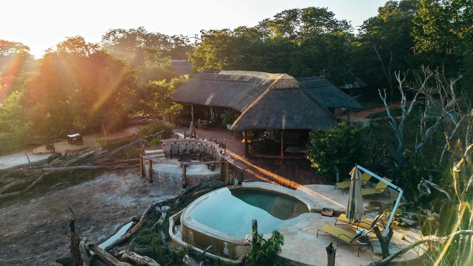 The plunge pool and thatched lounge at Khulu Bush Camp catch the low sun from above