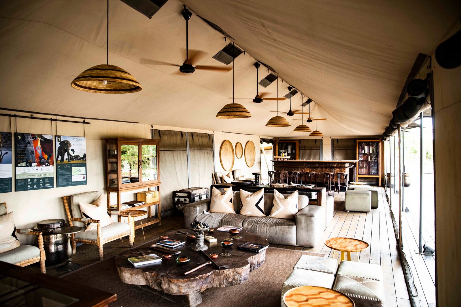Wilderness Little Makalolo's main lounge sits under canvas in Hwange, with sofas, a bar and lights