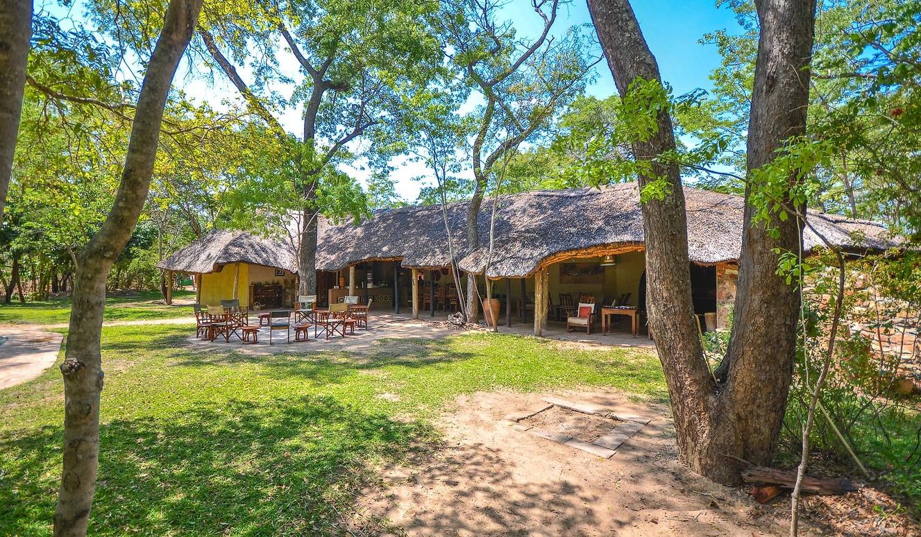 Miombo Safari Camp's thatched main building has tables on the lawn beneath the trees