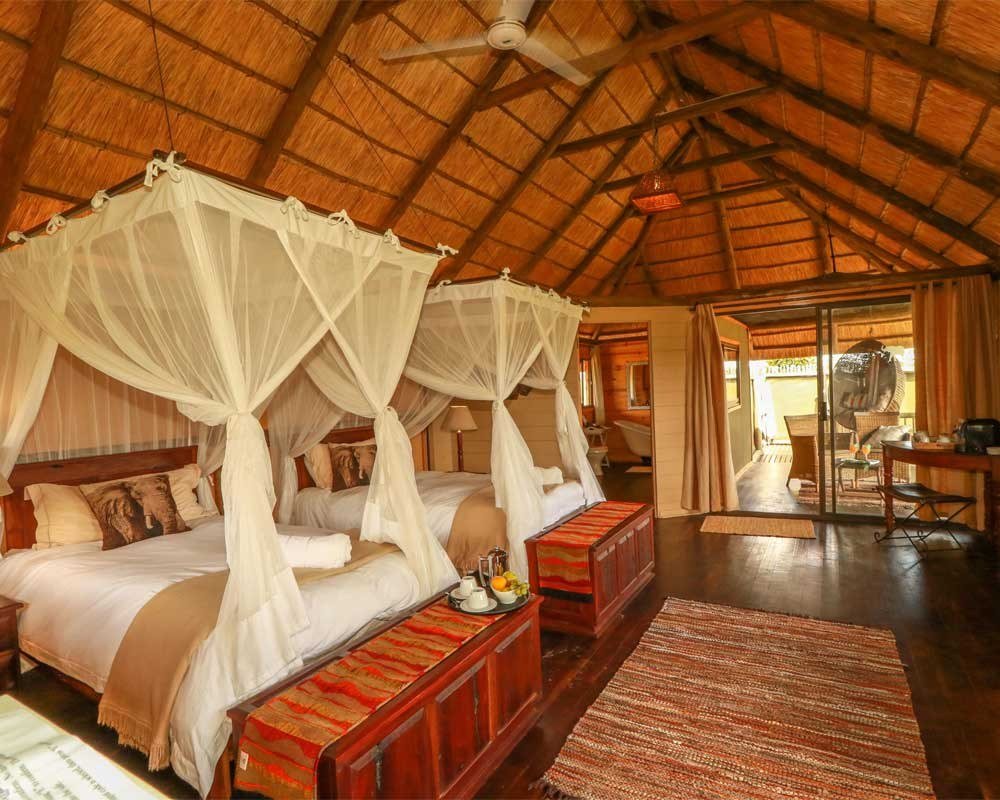 A family suite at Nehimba Lodge has two canopy beds under a thatched roof