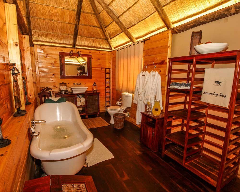 A bathroom at Nehimba Lodge has a clawfoot tub and wooden shelving