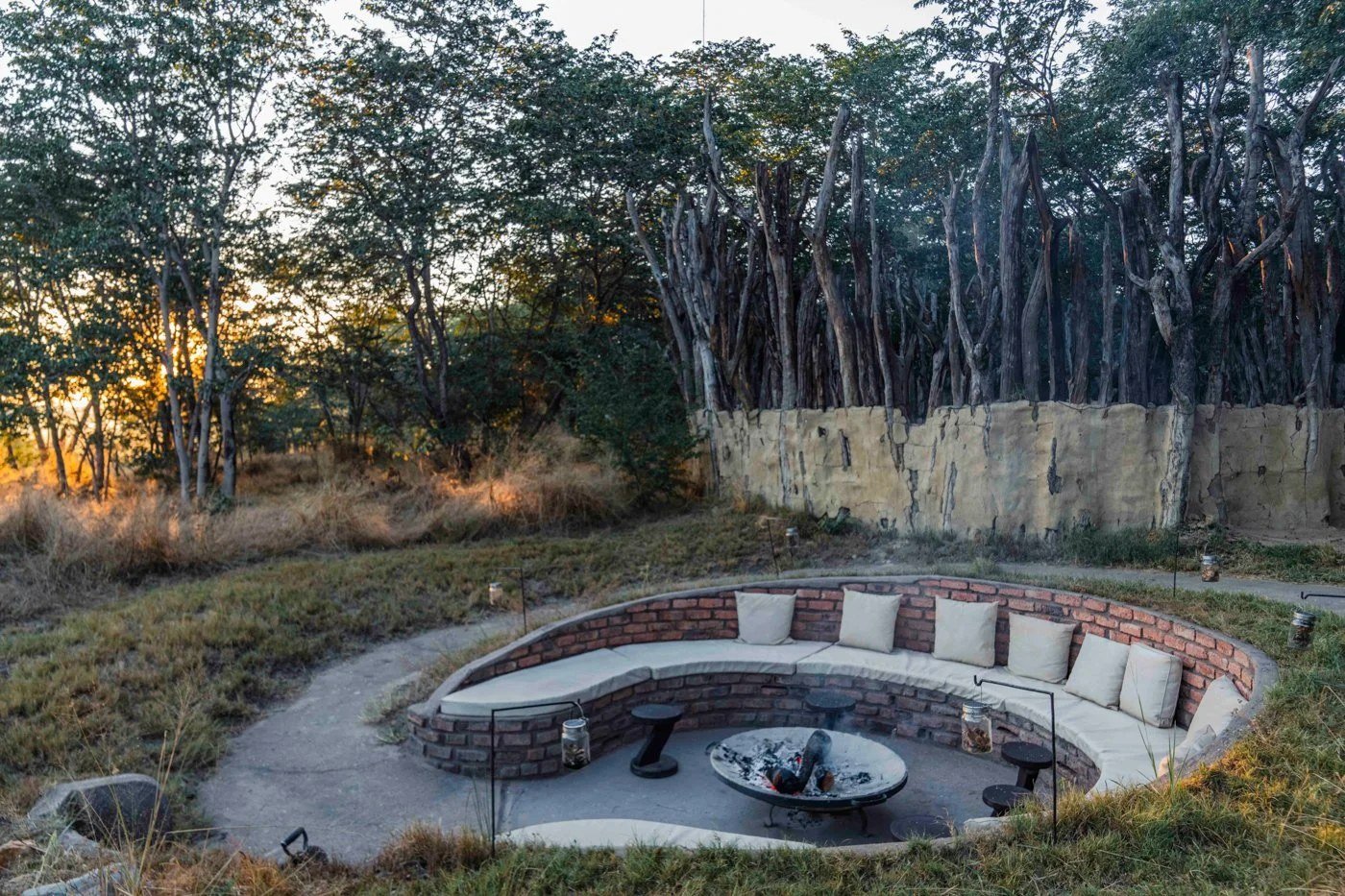 The sunken fire pit at Sable Valley Lodge has curved cushioned seating among the trees