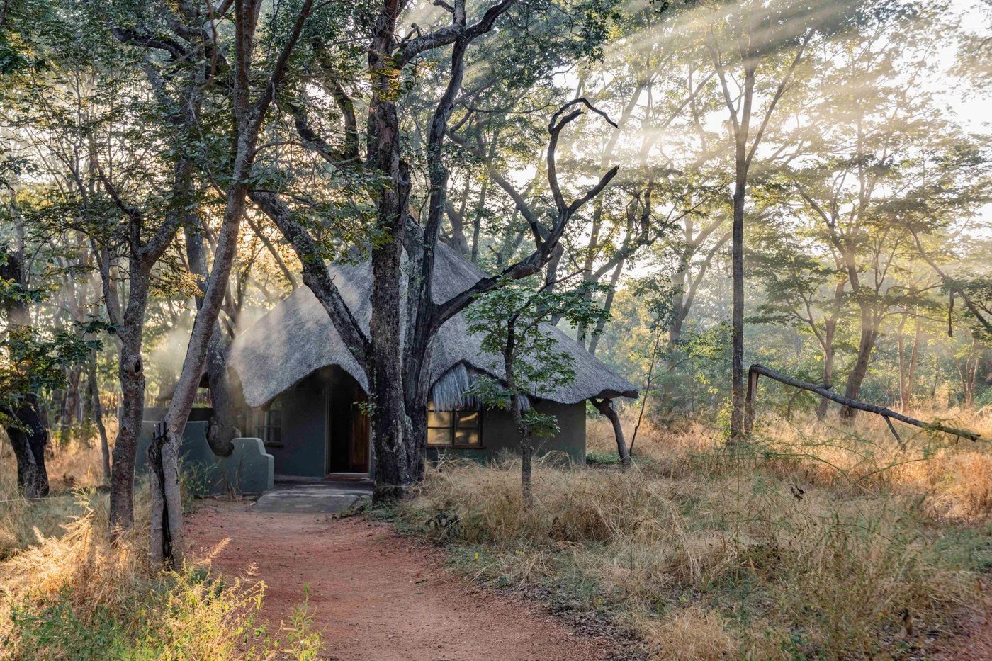 A thatched chalet at Sable Valley Lodge sits at the end of a sandy woodland path