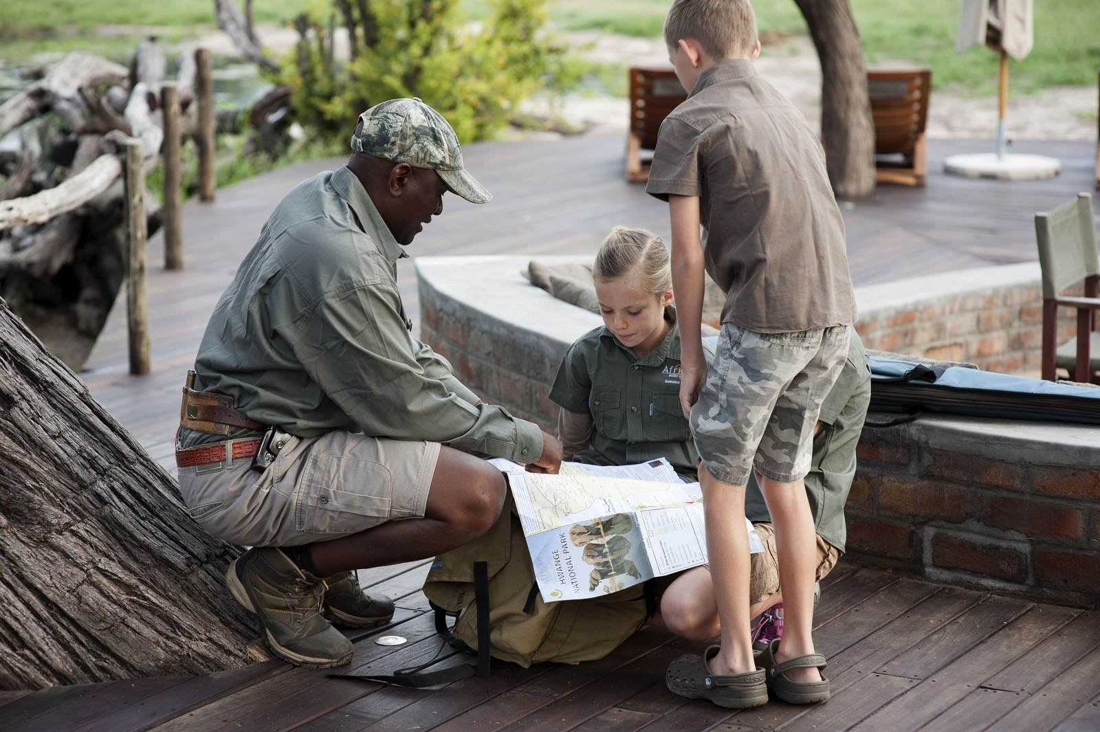 At Somalisa Acacia, a guide shows two children a map on the deck
