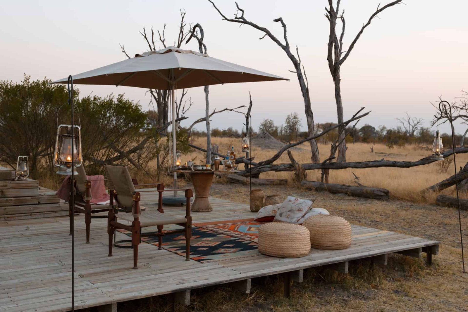 A deck with an umbrella and cushions sits in the bush at The Hide Safari Camp