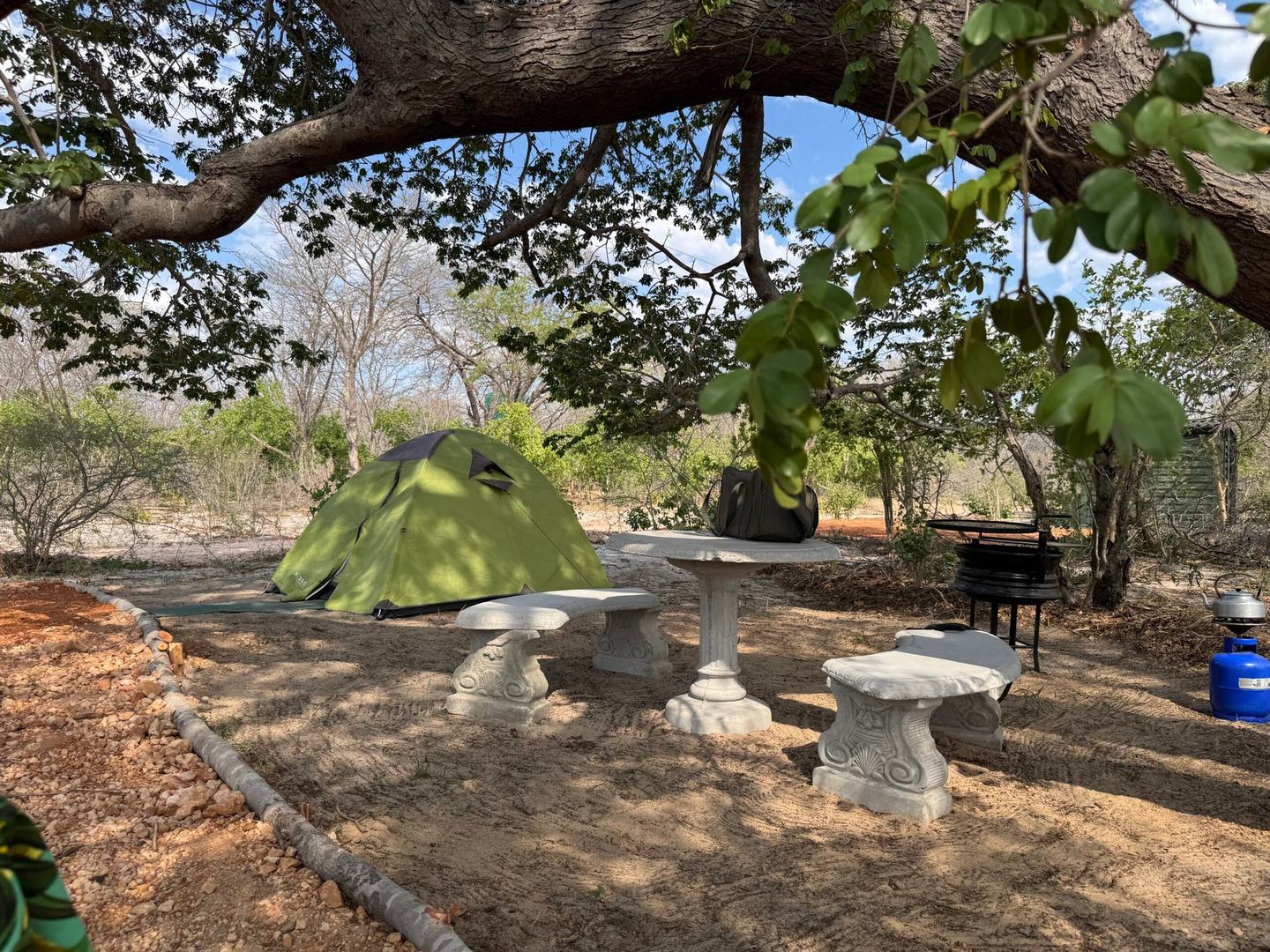 A small tent at The Track Shack is pitched beside a stone table and braai stand